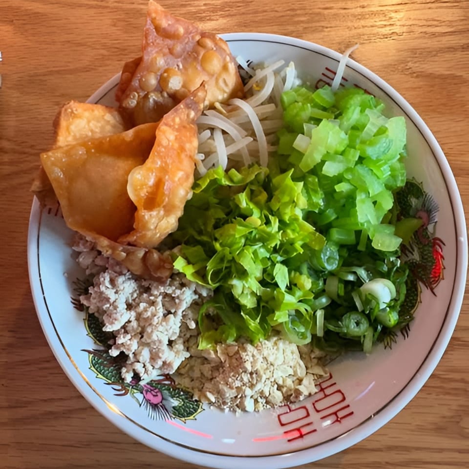 A bowl of Takashi Ramen's Japanese dish with fried wontons, ground meat, bean sprouts, and green onions.